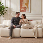 Couple assis sur le canapé modulable 2 places en chenille crème