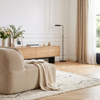 Chauffeuse sans accoudoirs beige vue de profil dans un salon